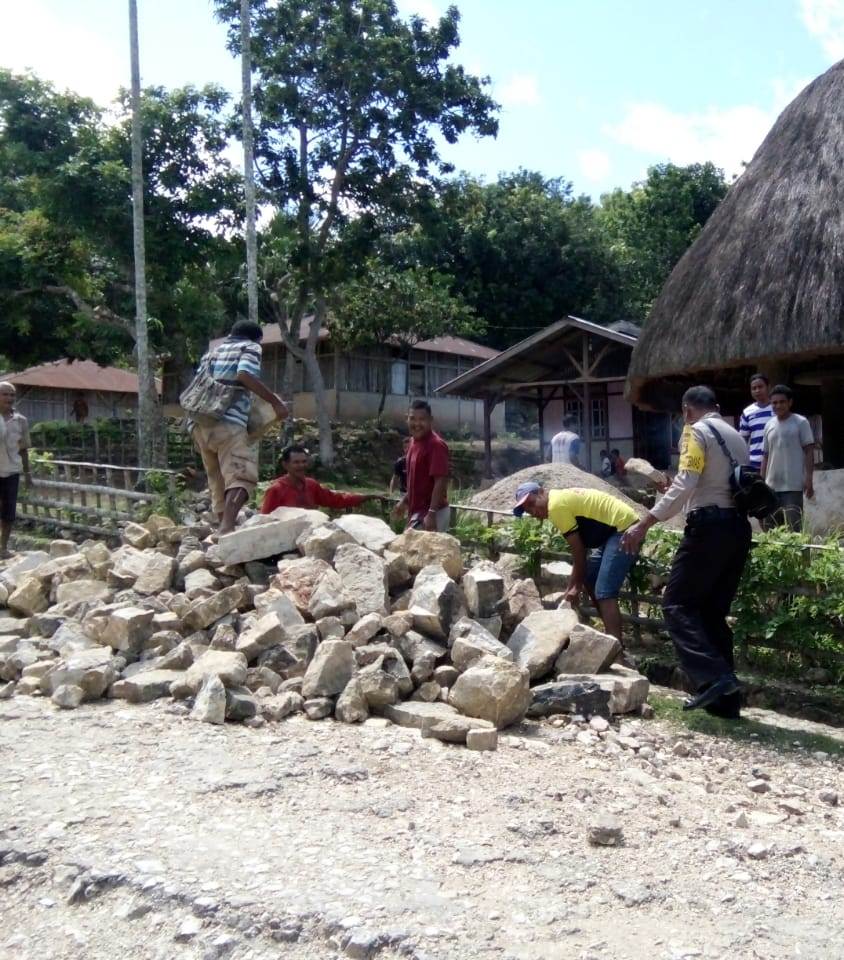 Mencegah terjadi kecelakaan , Bhabinkamtibmas Ajak Warga Bersihkan Tumpukan Batu di Badan Jalan
